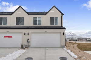 View of front of house featuring an attached garage, stucco siding, a mountain view, and ac unit