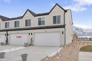 Townhome / multi-family property with a mountain view, ac unit, a garage, concrete driveway, and stucco siding