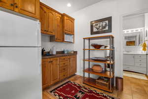 Kitchen featuring white appliances, a sink, brown cabinetry, and dark countertops