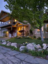 View of front facade featuring a balcony, stucco siding, an attached garage, aphalt driveway, and a front yard