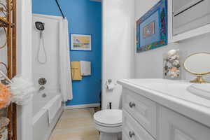 Bathroom featuring toilet, shower / bath combo, vanity, and baseboards