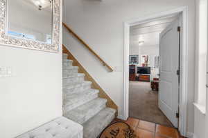 Stairway featuring tile patterned flooring and carpet