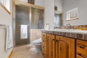Full bath with tile walls, toilet, vanity, and walk in shower