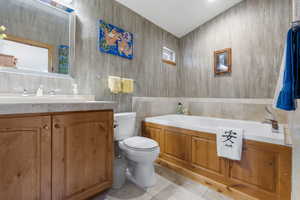 Full bath featuring a bath, tile walls, toilet, vanity, and tile patterned flooring