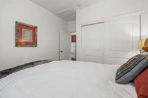 Bedroom featuring attic access, a closet, and freestanding refrigerator