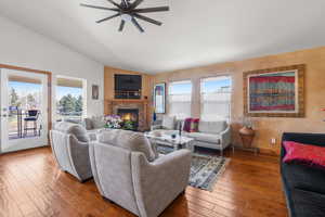 Living room with a fireplace, wood-type flooring, a ceiling fan, and lofted ceiling