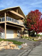 View of front facade featuring a garage, driveway, a balcony, and stucco siding