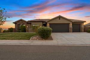 Mediterranean / spanish-style house featuring a tile roof, an attached garage, stone siding, and stucco siding