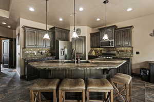 Kitchen with a kitchen bar, dark brown cabinetry, a sink, and stainless steel appliances