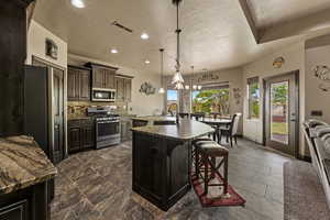 Kitchen featuring appliances with stainless steel finishes, visible vents, a kitchen bar, decorative backsplash, and a sink