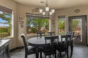 Dining room featuring baseboards, stone tile floors, a notable chandelier, and visible vents