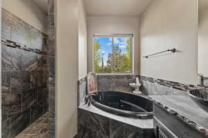 Bathroom featuring a tile shower, a bath, and vanity