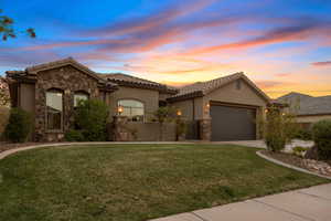 Mediterranean / spanish-style house featuring a garage, stucco siding, stone siding, a tile roof, and driveway