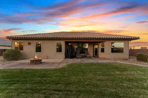 Back of house with a patio, a tiled roof, a fire pit, and a yard