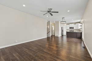 Unfurnished living room with ceiling fan, baseboards, dark wood finished floors, and visible vents