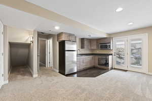 Kitchen featuring dark colored carpet, a sink, baseboards, and stainless steel appliances