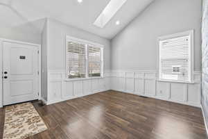 Foyer with recessed lighting, visible vents, lofted ceiling with skylight, a decorative wall, and wood finished floors
