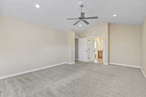 Unfurnished bedroom featuring ensuite bathroom, light colored carpet, vaulted ceiling, recessed lighting, and baseboards