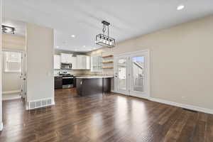 Kitchen with a peninsula, appliances with stainless steel finishes, dark wood-style floors, and visible vents