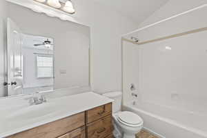 Bathroom with vanity, vaulted ceiling, shower / bath combination, a ceiling fan, and toilet