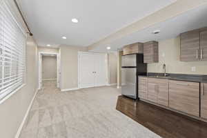 Kitchen with baseboards, a sink, freestanding refrigerator, dark countertops, and recessed lighting