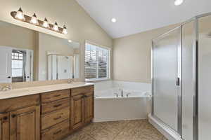 Full bath with a stall shower, a garden tub, a sink, and vaulted ceiling