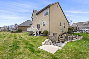 Rear view of property featuring a wooden deck, a lawn, and stucco siding