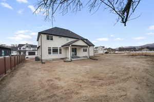 Rear view of house with central AC unit, fence, a residential view, and stucco siding
