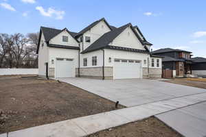 View of property exterior with a standing seam roof, roof with shingles, metal roof, an attached garage, and driveway