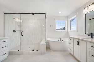 Bathroom with a freestanding bath, tile patterned floors, vanity, and a stall shower