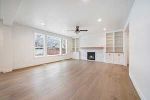 Unfurnished living room with baseboards, recessed lighting, light wood-style flooring, a ceiling fan, and a tile fireplace