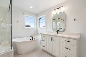 Bathroom with a soaking tub, a stall shower, tile patterned flooring, and vanity