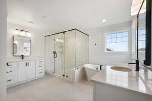 Full bath featuring a freestanding tub, two vanities, a stall shower, visible vents, and a sink