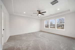 Empty room with visible vents, a ceiling fan, and a raised ceiling