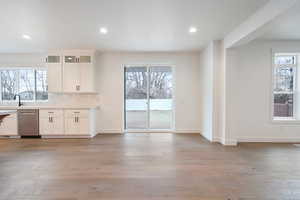 Kitchen with glass insert cabinets, white cabinets, dishwasher, light wood finished floors, and decorative backsplash