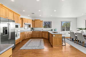 Kitchen with light wood-style flooring, under cabinet range hood, recessed lighting, and stainless steel appliances