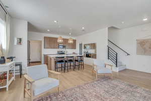 Interior space with light wood-type flooring, a kitchen island with sink, and stainless steel appliances