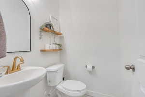 Bathroom with toilet, a sink, and baseboards