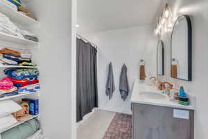 Bathroom featuring a sink, baseboards, double vanity, and a shower with curtain