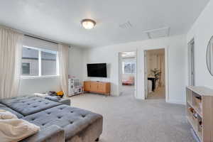 Bedroom with light carpet, visible vents, baseboards, and attic access