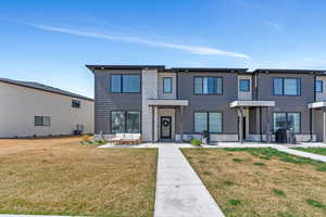 View of front of home featuring central air condition unit, stone siding, and a front lawn