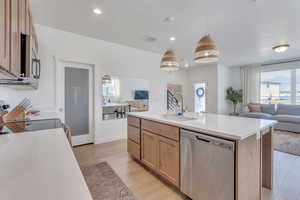 Kitchen featuring appliances with stainless steel finishes, a sink, light countertops, open floor plan, and light brown cabinets