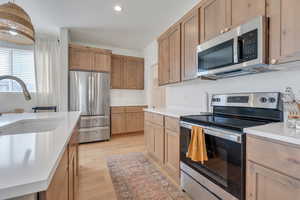 Kitchen with light wood-style flooring, light countertops, a sink, and appliances with stainless steel finishes