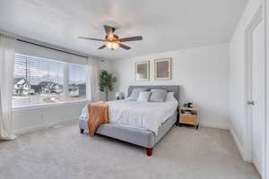 Bedroom featuring visible vents, baseboards, ceiling fan, and light carpet