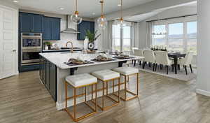 Kitchen with a mountain view, wall chimney range hood, a chandelier, double oven, and blue cabinetry