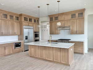 Kitchen featuring backsplash, stainless steel appliances, light stone counters, light wood finished floors, and recessed lighting