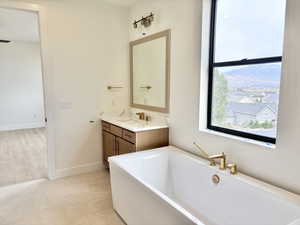 Full bath featuring a freestanding bath, vanity, and light tile patterned floors