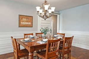 Dining area featuring wood flooring, a chandelier, and a wainscoted wall