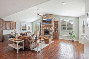 Family room area featuring vaulted ceiling, a fireplace, wood floors, large windows