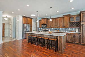 Kitchen with a breakfast bar, granite countertops, a kitchen island with sink, and stainless steel appliances